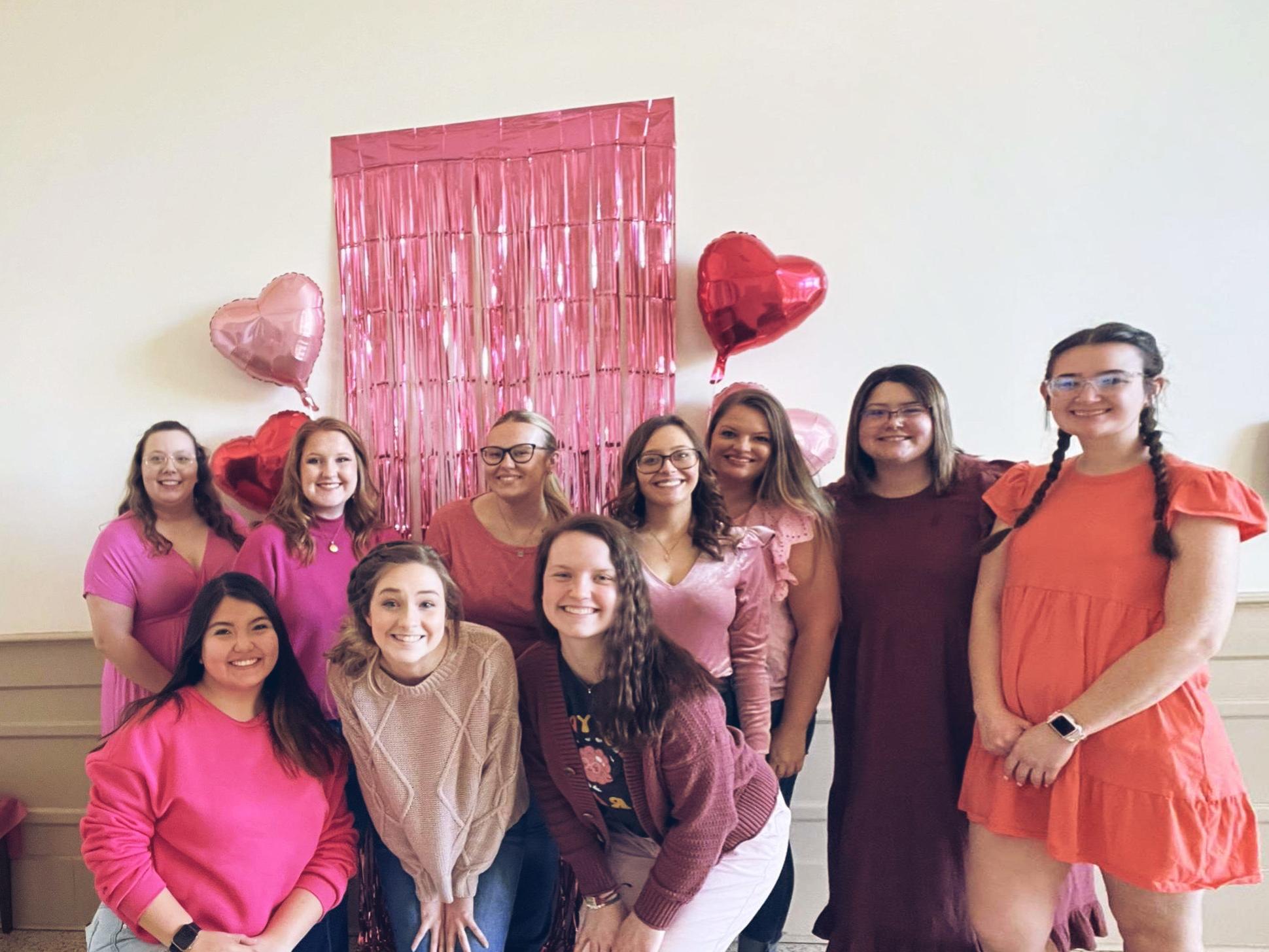 Education club members posing for a photo in front of Valentines decorations